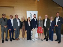 Neun Personen stehen für ein Gruppenfoto vor einem Banner der "Landesenergie" in Wien.