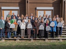 Gruppe von Personen hält Schilder mit dem EU-Logo vor einem Holzhaus in Österreich.