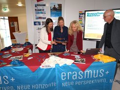 Erasmus+ Infostand mit drei Frauen und einem Mann in Österreich, die sich über Materialien beugen.
