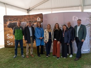 Gruppe von Personen vor einem Banner mit einem grauen Rind, Nationalpark Neusiedler See